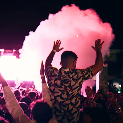 Man and crowd dancing with pink smoke in front Lust in Rio